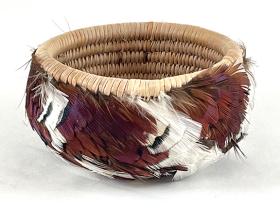 fine basket ornamented with white, brown and black feathers