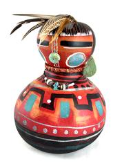 painted gourd of vibrant red with turquoise earrings and necklace, feathers on top