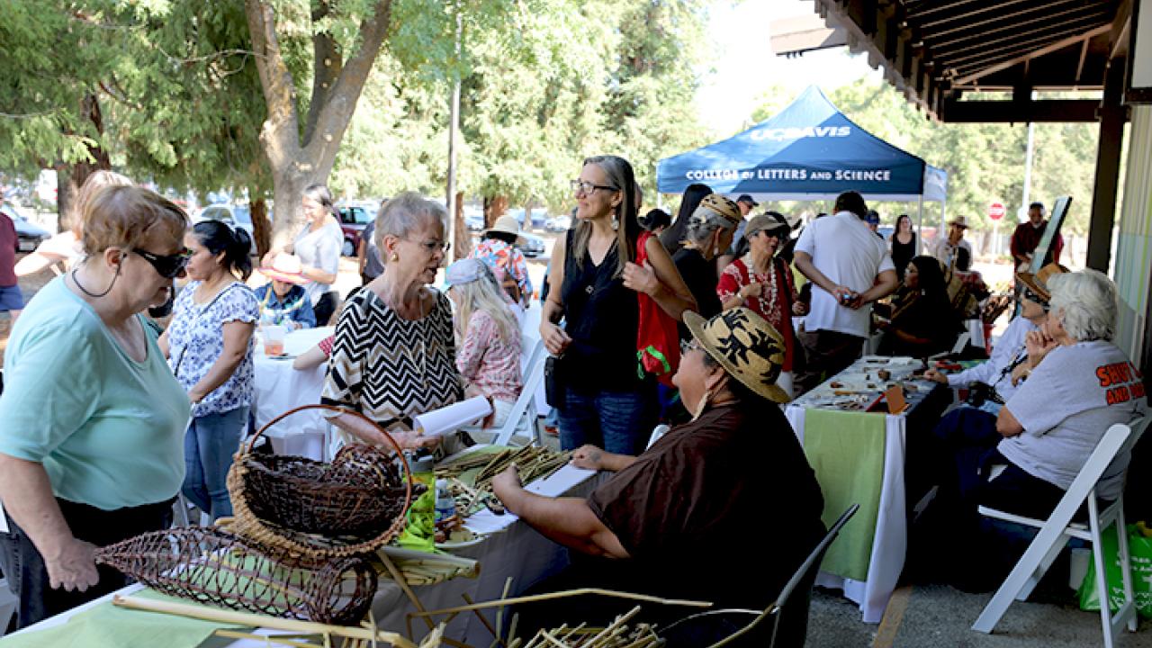 Artists sitting at tables with artwork greeting visitors