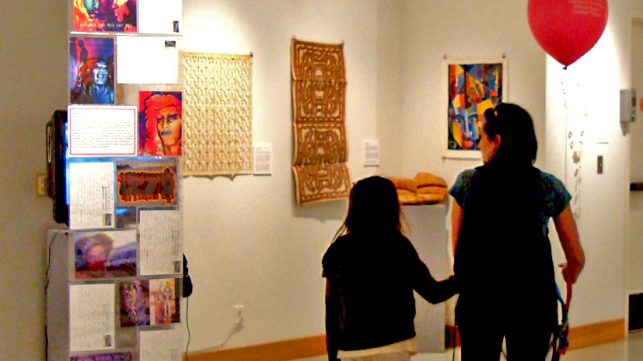 Woman and child holding balloon looking at art in the gallery