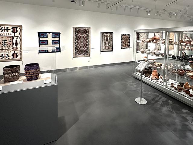 textiles on back wall and exhibit cases of pottery