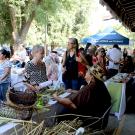 Artists sitting at tables with artwork greeting visitors