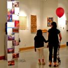 Woman and child holding balloon looking at art in the gallery